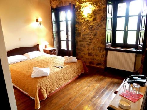 a bedroom with a bed and a table and windows at Ξενώνας Αρχοντικό Πρεδάρη in Goura