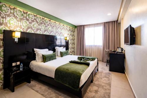 ein Hotelzimmer mit Bett und Fernseher in der Unterkunft Hôtel du Golf Mohammedia in Mohammedia