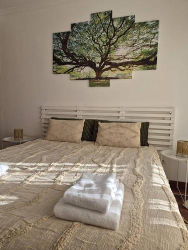 a bedroom with a bed with a tree on the wall at LandS in Caniço