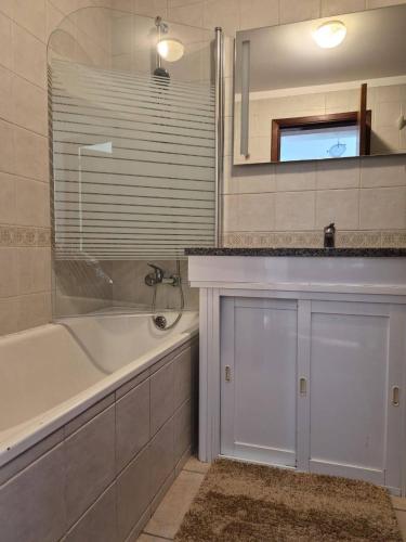 a bathroom with a tub and a sink and a mirror at LandS in Caniço