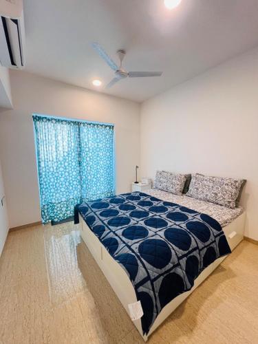 a bedroom with a bed and a blue curtain at Serene white studio - 2nd floor in Dehu Road