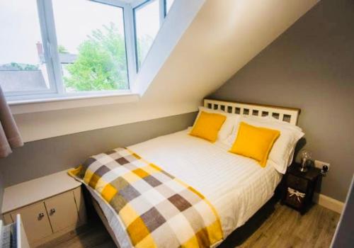 a bedroom with a bed with yellow pillows and a window at Church Lane Holiday Home, Warrenpoint in Warrenpoint