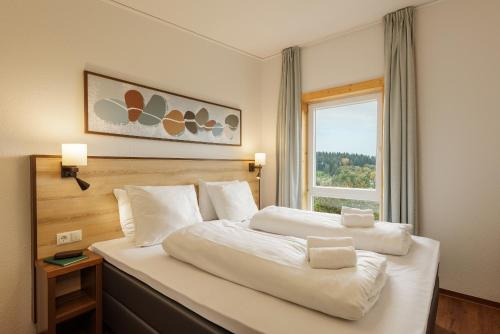 a bedroom with a large white bed with a window at Center Parcs Bostalsee Saarland in Nohfelden