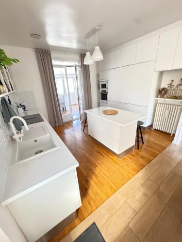 a white kitchen with a sink and a table at Large house with garden in Vulaines-sur-Seine