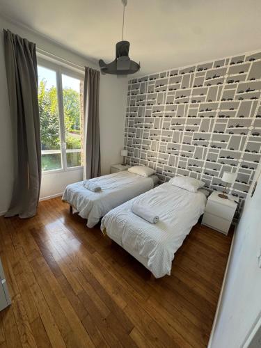 two beds in a bedroom with a brick wall at Large house with garden in Vulaines-sur-Seine