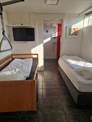 a room with two beds and a flat screen tv at De Golfakker in Hollum