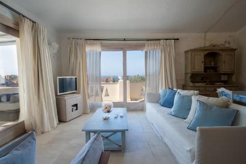 a living room with a white couch and blue pillows at Hotiday Apartment Liscia Di Vacca in Porto Cervo