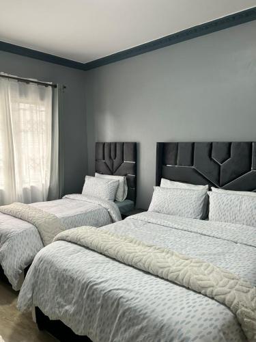 a bedroom with two beds with white sheets and a window at Crompton Gardens 786 in Durban