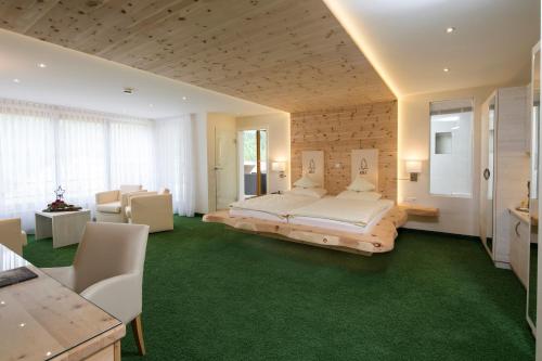 a bedroom with a large bed and green carpet at Tanne Tonbach - Wellness & Wohlfühl Hotel in Baiersbronn