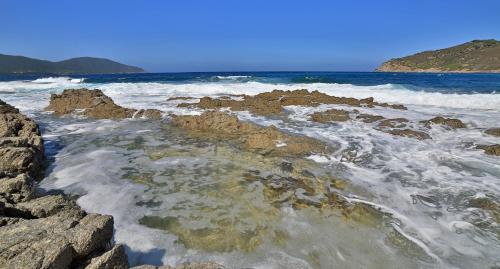 a beach with rocks and waves in the ocean at Village de vacances Paese di Lava, Grand Ajaccio in Alata