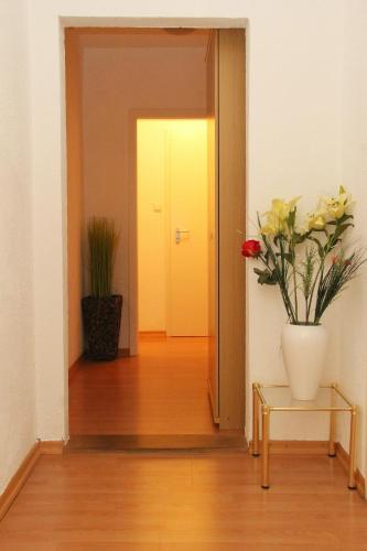 a hallway with a vase of flowers and a door at Hotel Taverne Inos in Hannover