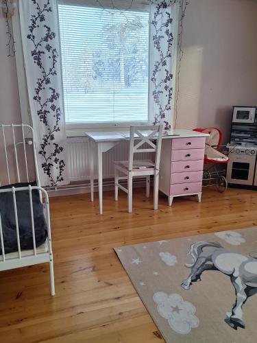 a bedroom with a desk and a table and a window at MarrasVilla in Marrasjärvi