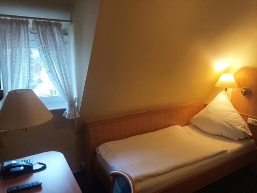 a hotel room with a bed and a window at Hotel Büker in Erwitte