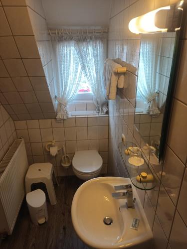 a bathroom with a sink and a toilet and a window at Hotel Büker in Erwitte