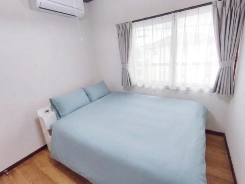 a bedroom with a large white bed and a window at みん民ハウス上浅田 in Hamamatsu