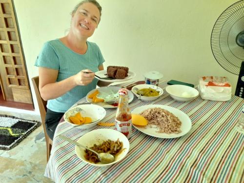 a woman sitting at a table with food at KADUPUL Hiriketiya in Hiriketiya