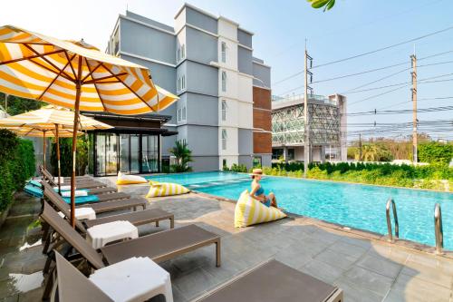 a woman sitting by the pool at a hotel at Fourium Pattaya Hotel and Serviced Residence in Pattaya South