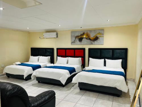 a room with three beds and a couch at Lugogo Guesthouse in Thohoyandou