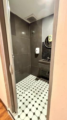 a bathroom with a shower with a black and white tiled floor at City Hub Hotel Sitiawan in Sitiawan
