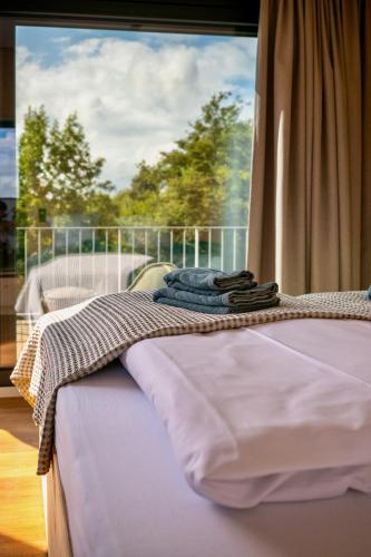 a bed with towels on it in front of a window at Ostsee Baumhaushotel - Auf Höhe der Baumkronen in Wangels
