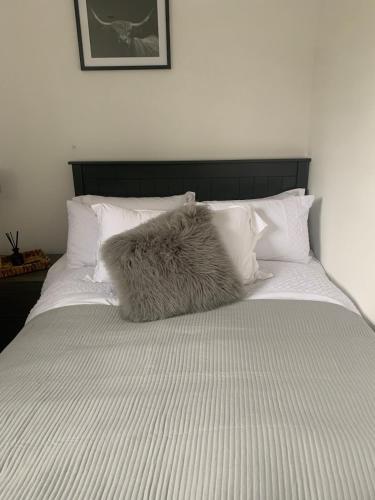 a white bed with a furry pillow on it at The Little Red lion in Thorpe