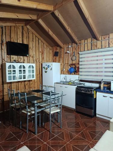a kitchen with a table and a stove and a refrigerator at cabaña vale in Coñaripe