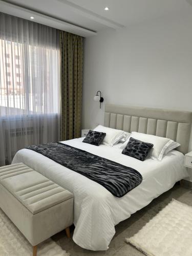 a white bedroom with a large bed and a window at Jasmine Apartment Tunis in Tunis