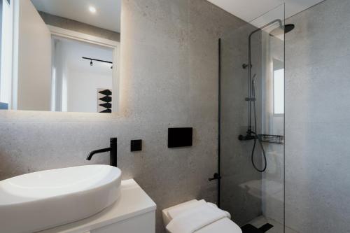 a bathroom with a white sink and a shower at The Edge Piraeus Luxury Residences in Piraeus