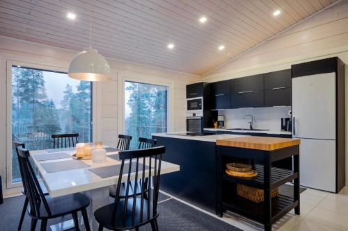 a kitchen with a dining table and a kitchen with black cabinets at Villa Länsihuippu Incl WiFi, Pool table, AC, Jacuzzi for extra fee in Himos