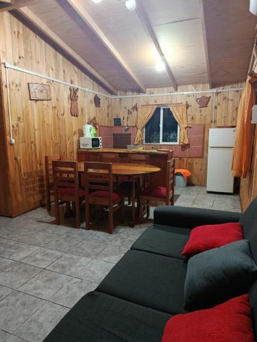 a living room with a table and a kitchen at cabaña zoila in Coñaripe