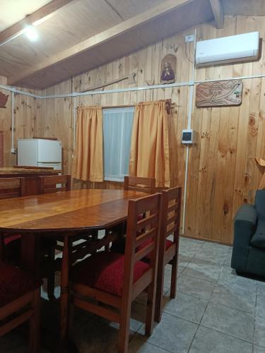 a dining room with a wooden table and chairs at cabaña zoila in Coñaripe