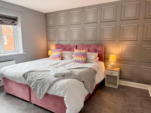 a bedroom with a large bed with a red headboard at Chislehurst House in Bedford