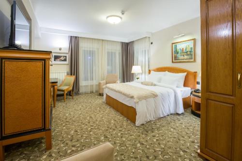um quarto de hotel com uma cama e uma televisão em Hotel Sterling Garni em Belgrado