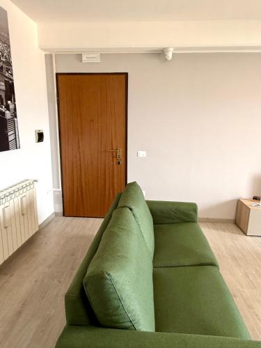 a green couch in a living room with a wooden door at La Casa Di Elda in Terni