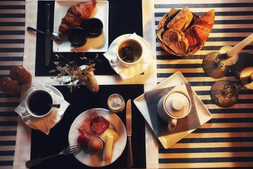 a table topped with plates of pastries and cups of coffee at Hotel Les Terrasses in Annecy