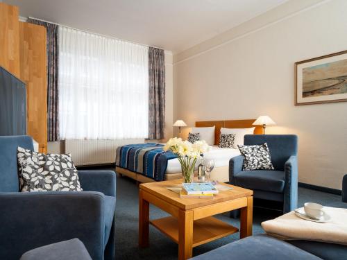 a hotel room with a couch and chairs and a table at Hotel Gutenberg in Westerland
