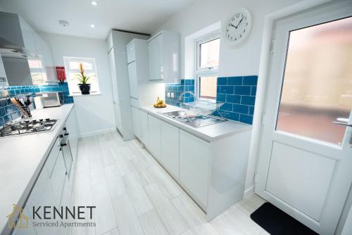 a kitchen with white counters and a clock on the wall at Franklin Lodge in Reading