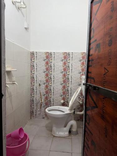 a bathroom with a toilet and a pink bucket at HOTEL INDRANEEL Hanuman Garhi in Ayodhya