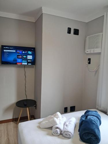 a room with a bed with towels and a tv at Apartamento completo e perfeito, Ao lado da Weg in Jaraguá do Sul