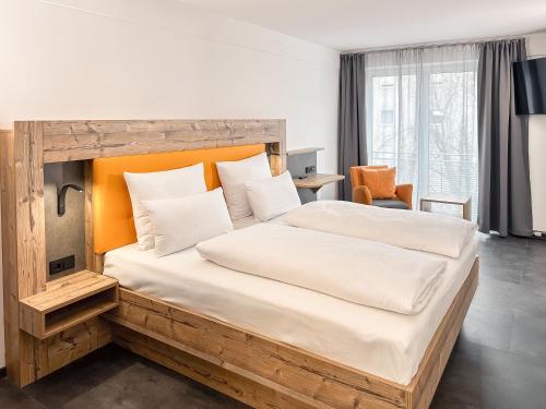 a bedroom with a large bed with a wooden headboard at THE GOOD ONE Hotel Landshut in Landshut