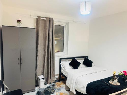 a white bedroom with a bed and a window at East London Suites 1 in London