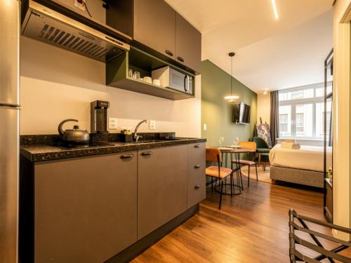 a kitchen with a sink and a living room at Xtay Cais Rooftop -Estúdios completos e Rooftop para o Rio Guaíba in Porto Alegre