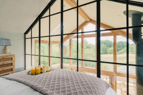 a bedroom with a bed with a large window at The Tractor Shed in Combrook
