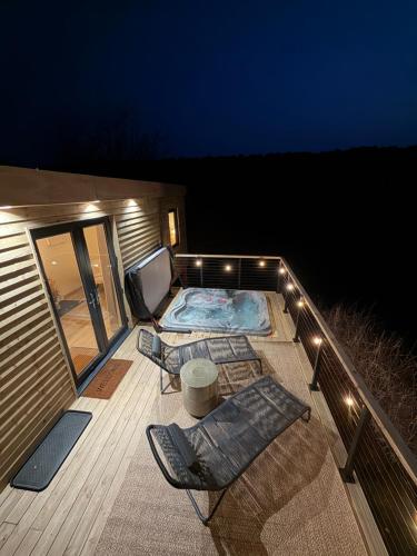 a deck with two chairs and a table and lights at Luxury Shepherds Hut with Hot Tub Valley Views in Scarborough