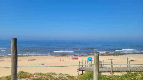 a beach with a bench and people on the beach at Granja Beach Front in São Félix da Marinha