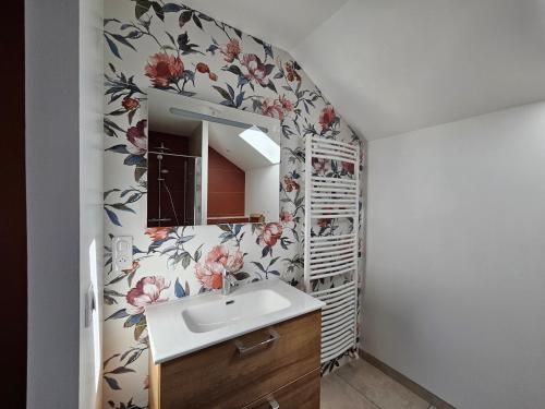 a bathroom with a sink and a flower patterned wall at Gîte Le Granit des Champs in Mainsat