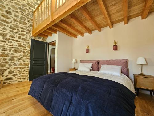 a bedroom with a large bed and a stone wall at Gîte Le Granit des Champs in Mainsat