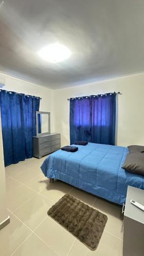 a bedroom with a blue bed and blue curtains at Green House Boca Chica in El Higo
