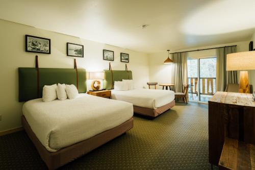 a hotel room with two beds and a table at Seward Windsong Lodge in Seward