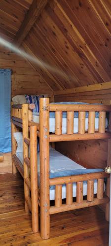 two bunk beds in a log cabin with wooden ceilings at Texarkana KOA Journey in Texarkana